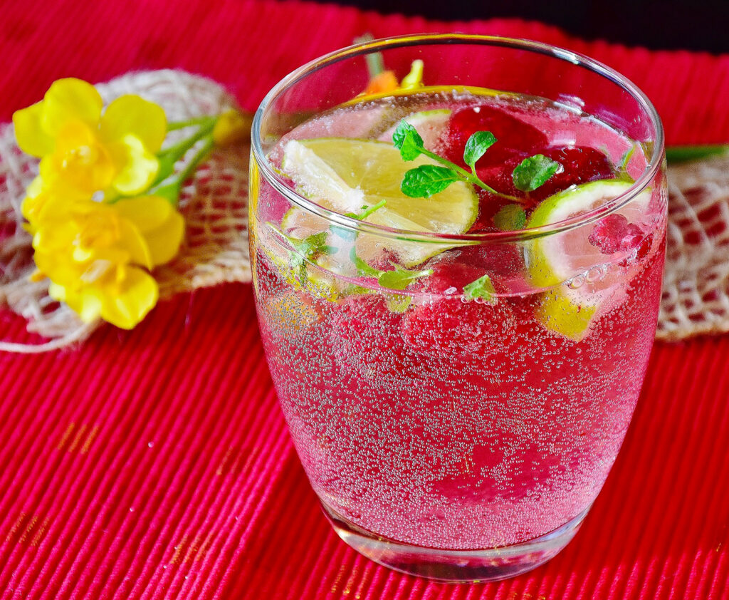 Eau pétillante avec des baies et du citron sur nappe rouge