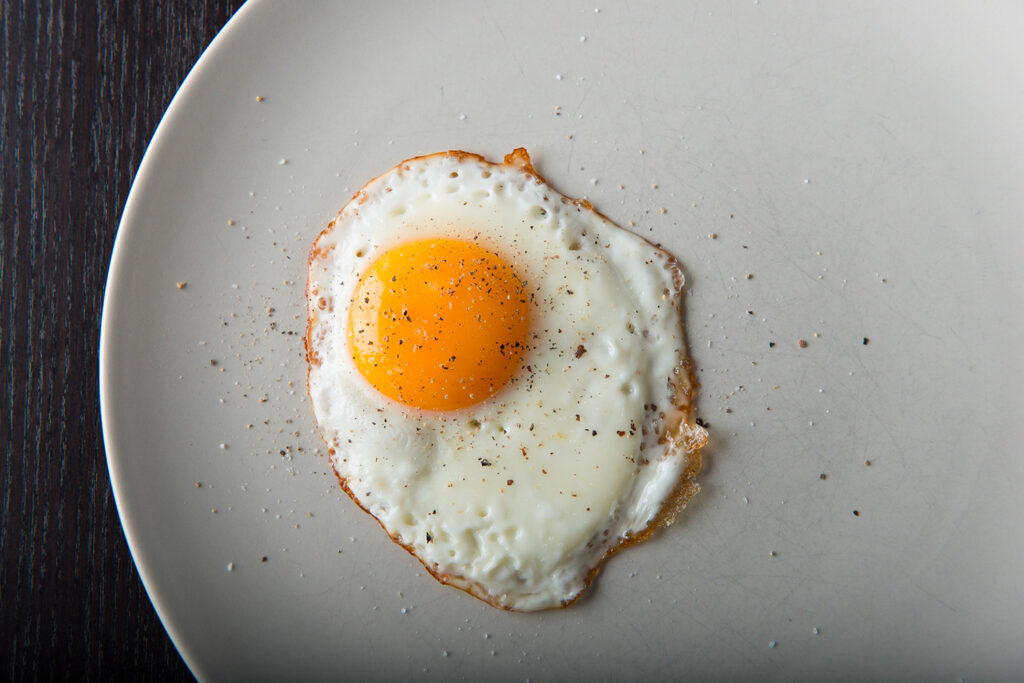 Œuf au plat avec du sel dans une assiette