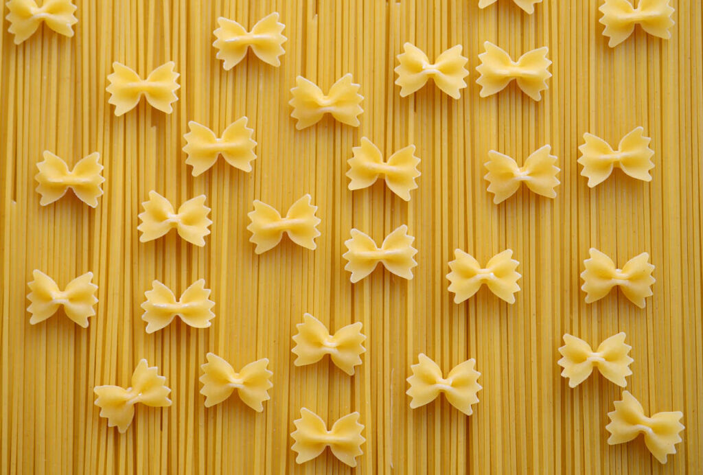 Pâtes spaghetti avec des pâtes farfalles par-dessus pour représenter les glucides